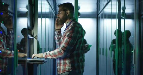 Man Working in Server Room Talking on Cellphone