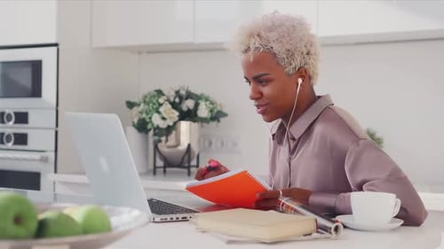 Une jeune femme concentrée passe un appel vidéo, donne des cours particuliers, écrit des notes, enseignement