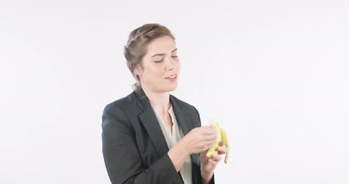 Woman eating a banana on a white studio background