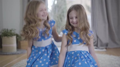 Adorable Sisters in Matching Dresses Smiling Affectionately