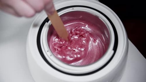 Depilation Master Melts Wax for the Procedure in the Heater and Mixing It Using a Spatula