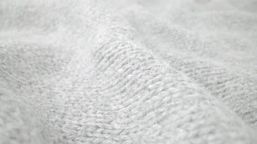 Extreme detail view of sheep wool cloth texture flowing in macro dolly shot.