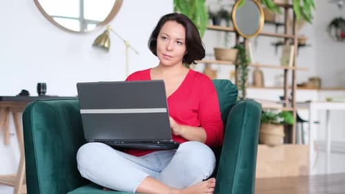 Woman Working on Laptop in Green Chair at Home