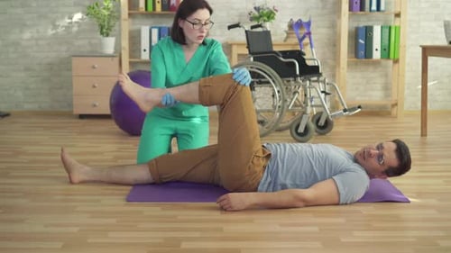 Therapist Assisting Man Stretching Leg Indoors