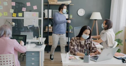 Young Arab Man Wearing Mask Doing Highfive Greeting Colleagues in Office During Pandemic