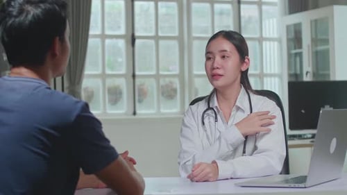 Asian Woman Doctor Is Talking With Young Male Patient During Consultation In A Health Clinic