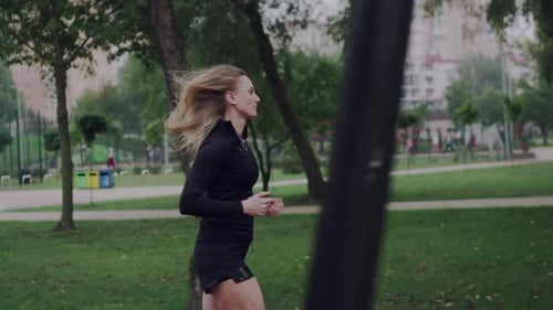 Woman Jogging Through Park on a Cloudy Day