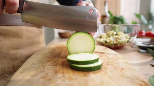 Slicing Fresh Zucchini on Cutting Board in Kitchen