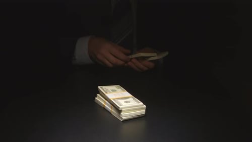 Man Stacking Bundles of Cash on Table