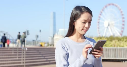 Young Woman Using Phone in City Park