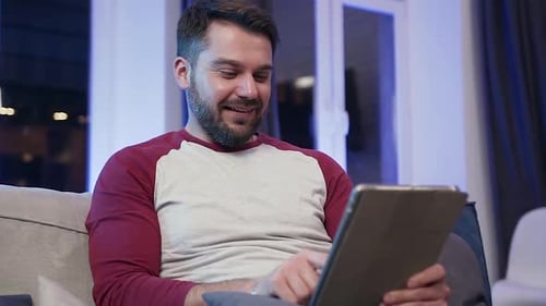 Man Smiling Using Tablet on the Couch
