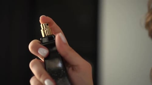 Eine Frau hält Parfum in ihren Händen und spritzt sie