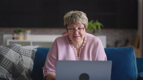 Vovó alegre está dando as boas-vindas aos interlocutores do chat de vídeo on-line Mulher idosa está se comunicando