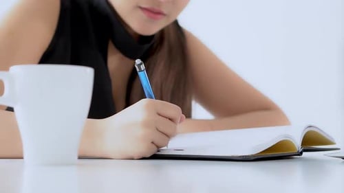 Woman writing in notebook at desk