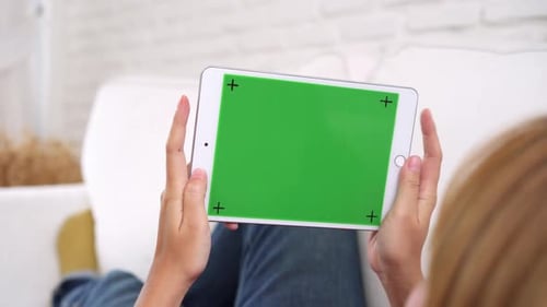 Young asian woman using black tablet device with green screen. Asian woman holding tablet.