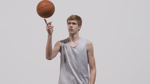 Portrait of a Young Guy Basketball Player Looking at the Camera and Spins the Ball on His Finger