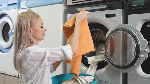 Blonde Woman Puts Laundry in Washing Machine