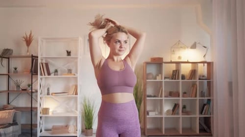 Woman Ties Up Hair in Sports Bra Indoors