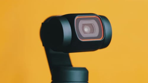 Black Camera Rotating on a Yellow Background