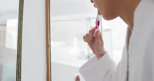 Woman Brushing Teeth in Bathroom with Towel