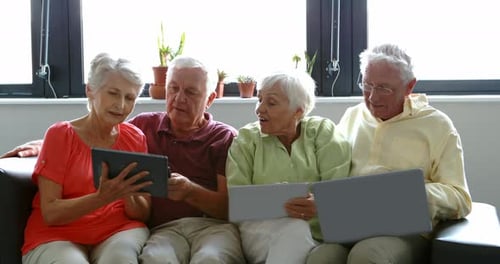Seniors Using Technology and Interacting on Sofa