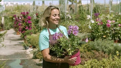 Happy Middle Aged Female Gardener Holding Potted Flowering Plant