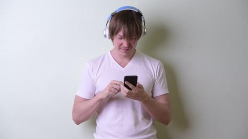 Young Adult Using Smartphone with Headphones On