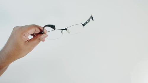 Hand Holding Pair of Metal Framed Glasses