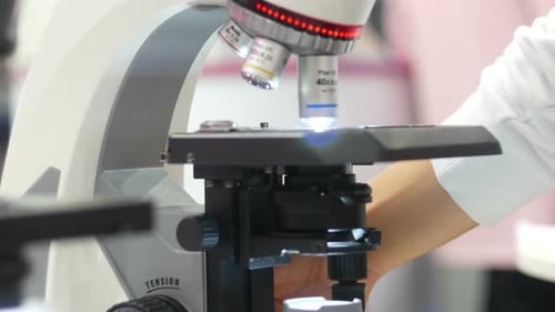 Hand Adjusting Focus on Scientific Microscope
