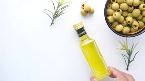 Bottle of Olive Oil and Fresh Olive in a Container on Table