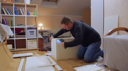 Ein Mann mit Schraubenzieher baut Möbel zusammen