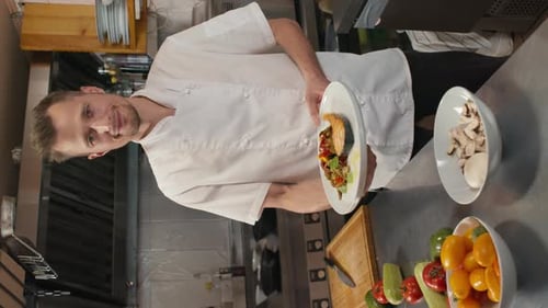 Chef Holds Plate of Fish Entree in Kitchen