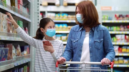 Mãe e filha comprando doces no supermercado durante a pandemia