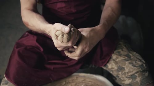Ernsthafte Frau, die bei Pottery Wheel im Studio arbeitet, bereitet Ton vor, um den Teller
