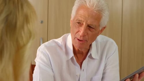Older Man Talking with Woman While Holding Tablet