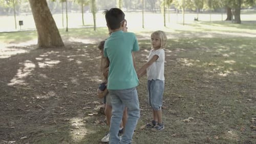 Children Play Together Holding Hands in Grassy Park