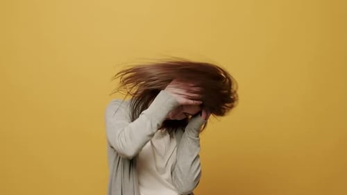 Smiling Woman Waving Her Hair Against Yellow Background