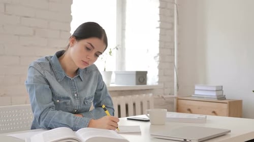 Focused Young Adult Studying at Home Desk