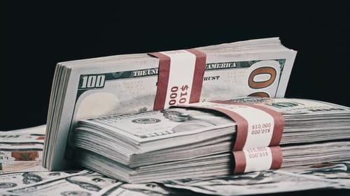 Bündel von Dollar liegen auf einem Geldhaufen und rotieren auf schwarzem Hintergrund