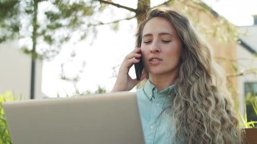Cheerful Businesswoman Talking on Phone and Using Laptop in Park