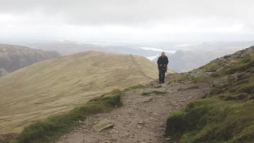 Man hiking on mountain trail in a cloudy day