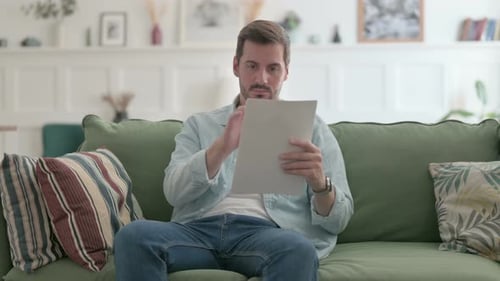 Man Reviewing Documents While Sitting on Sofa
