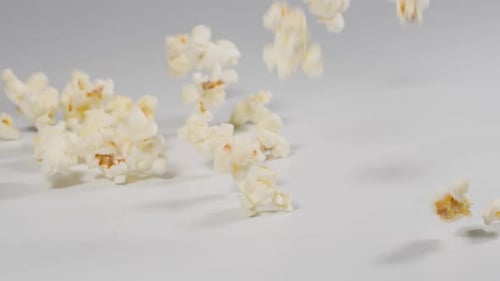 Fresh popcorn falling onto a white surface in slow motion