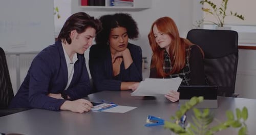 Three Colleagues Collaborate Around Table in Office