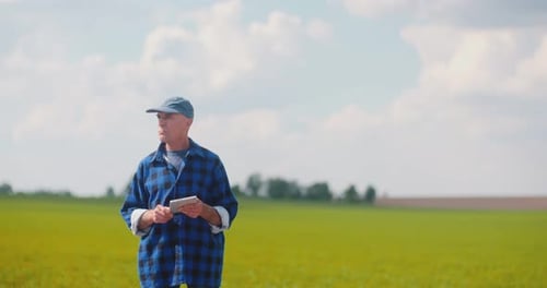 Farmer Using Digital Tablet While Examining Field