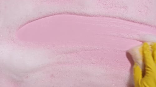 Hand Cleaning Pink Surface with Sponge and Bubbles
