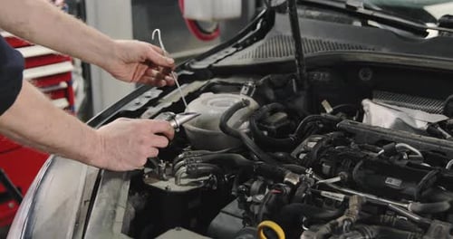 Mechanic Inspecting Car Engine with Tools