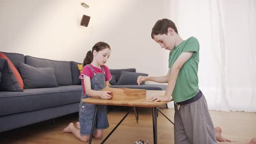 Junge und Mädchen spielen gemeinsam ein Holztischspiel im Wohnzimmer