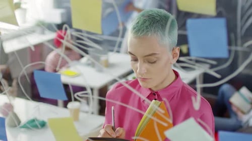 Young Female Creative Specialist Writing in Planner