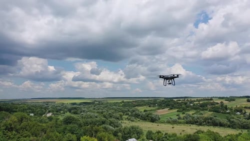 Drone overflying field. Drone quadcopter with digital camera flying over countryside